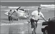  ?? AP/The Daytona Beach News-Journal/DAVID TUCKER ?? Volusia County Beach lifeguards use a winch to pull an airplane ashore after a crash in which the pilot was helped ashore, but refused treatment Tuesday, in Daytona Beach Shores, Fla.