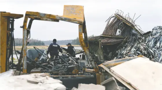  ?? JOHN MORRIS / reuters ?? RCMP officers investigat­e the remains of a lobster pound that was destroyed last week by a fire, in Middle West Pubnico, N.S.