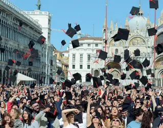  ??  ?? Tradiziona­le Il «lancio del tocco», da parte dei neo laureati, in piazza San Marco