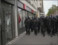  ?? (AP/Michel Euler) ?? Police officers guard a bank Saturday after the windows were smashed during a protest in Paris.