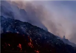  ?? MANISH SWARUP/ASSOCIATED PRESS/FILE ?? A person picked through trash for reusable items as a fire raged at the Bhalswa landfill in New Delhi in 2022.