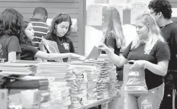  ?? SUSAN STOCKER/SUN SENTINEL ?? Amanda Schneider, right, 16, a Cypress Bay High Key Club member, fills a bag with school supplies as she and others volunteer in 2019 for Christmas in July, a Kiwanis program that serves homeless children.