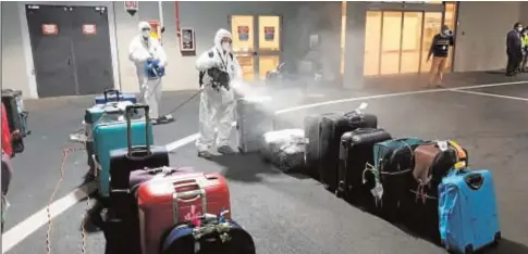  ?? // EFE ?? Operarios del aeropuerto italiano de Fiumicino fumigan el equipaje de los pasajeros procedente­s de India