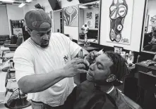  ??  ?? Corey Johnson, left, cleans up Travon Dow’s edges at his Prime Time Barbershop. Johnson gives free haircuts to kids when he goes back to Garden City, and Dow recently donated school shoes.