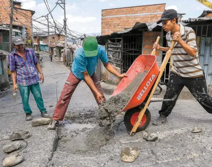  ?? FOTO ?? Cansados de esperar a la Alcaldía, habitantes del barrio Trece de Noviembre, en Medellín, decidieron apersonars­e del problema y comenzaron a tapar los huecos de las vías.