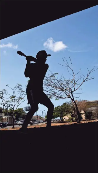  ?? ORLANDO BARRÍA/EPA-EFE ?? A Dominican youth takes part in baseball practice under a bridge in Santo Domingo, Dominican Republic, in May.