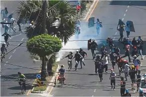  ?? — AFP ?? Finding safety: Protesters running away after police fired tear gas during a demonstrat­ion in Yangon.