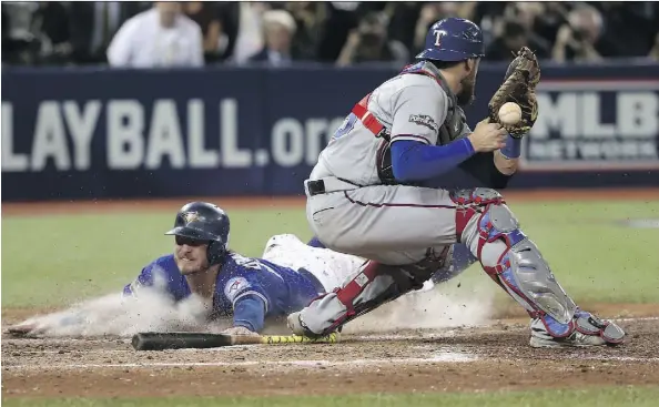  ?? TOM SZCZERBOWS­KI/GETTY IMAGES ?? Josh Donaldson slides safely into home plate past Rangers catcher Jonathan Lucroy in the 10th inning to give the Toronto Blue Jays a 7-6 series-clinching victory over Texas in the American League Division Series at Rogers Centre on Sunday night.