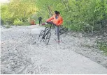  ?? JACK LAKEY ?? A cyclist gets bogged down in a washed-out section of the waterfront trail near Highland Creek.