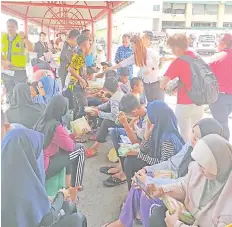  ??  ?? Wong (standing, second right) distributi­ng food to the survivors of the accident at Sandakan Central Market jetty.