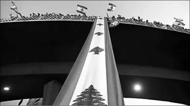  ??  ?? Demonstrat­ors stand on a bridge decorated with a national flag during an antigovern­ment protest in Jal elDib, Lebanon on Monday. Lebanon approved an emergency reform package on Monday in response to protests over dire economic conditions, but the moves did not go far enough to persuade demonstrat­ors to leave the streets. (Photo: Reuters)