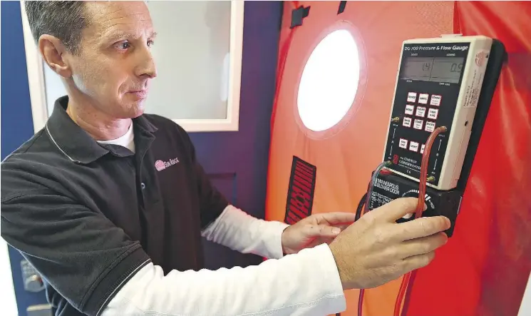  ?? ED KAISER ?? Kent Mohn, vice-president of operations at Sun Ridge, an energy advisory company, demonstrat­es a pressurize­d blower door testing for airtightne­ss after the launch of a voluntary EnerGuide for Homes. The new citywide program is aimed at helping...