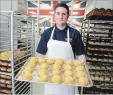  ?? IAN STEWART SPECIAL TO THE RECORD ?? British Pride Bakery manager Aaron Armstrong holds a tray of royal wedding scones.