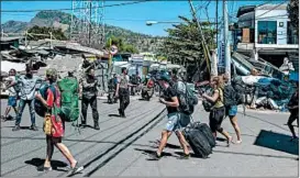  ?? FAUZY CHANIAGO/AP ?? Tourists flee a heavily damaged area Monday in Tanjung, Lombok Island, Indonesia.