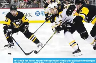  ??  ?? PITTSBURGH: Matt Hunwick #22 of the Pittsburgh Penguins reaches for the puck against Patrice Bergeron #37 of the Boston Bruins at PPG PAINTS Arena On Sunday in Pittsburgh. — AFP
