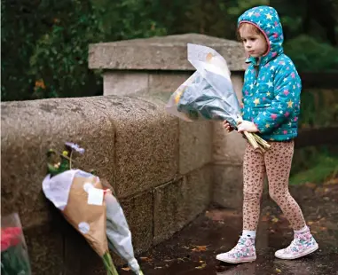  ?? ?? Tribute: A young wellwisher braves the rain to leave flowers outside Balmoral yesterday