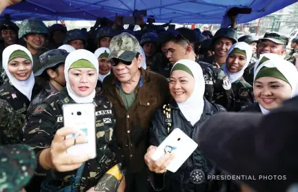  ??  ?? Philippine President Rodrigo Duterte poses with female soldiers during his visit to Bangolo town in Marawi city on Tuesday. (Reuters)