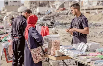  ?? — AFP ?? People shop from vendors in an open-air market amidst destructio­n in Gaza.