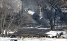  ?? THE ASSOCIATED PRESS ?? A crew member walking near the scene of a train derailment Feb. 17 near Mount Carbon, W.Va. Tank cars carrying oil or ethanol by rail urgently need to be retrofitte­d to make them more fire-resistant after a spate of explosive accidents in recent months...