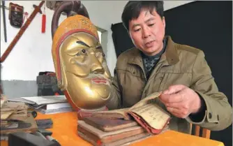  ??  ?? Chen reads manuals on mask making, which have been handed down from past generation­s of his family, at home in Pingxiang on Dec 28.