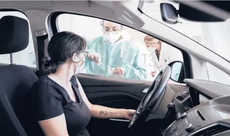  ?? ALESSANDRO GRASSANI/THE NEW YORK TIMES ?? A motorist receives the AstraZenec­a vaccine Monday at a drive-through facility in Milan. Italy joined Germany and France in suspending the use of the COVID-19 vaccine amid concerns about blood clotting.