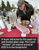  ??  ?? A buyer attracted by this good cut and frosted glass vase. The Czech “Victoire” car mascot priced at €120 is in the foreground