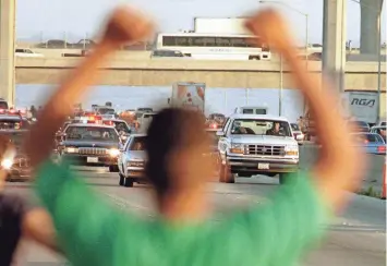  ?? SAM MIRCOVICH PHOTOS/REUTERS ?? A man cheers as the Ford Bronco carrying OJ Simpson, right, is chased by dozens of police cars during a pursuit through Los Angeles area freeways on June 17, 1994.