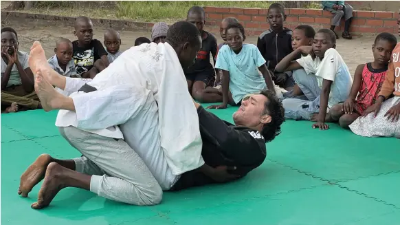 ?? Tim Albone ?? Jiu-jitsu instructor Cezar Takeyoshi Ikehara teaches orphans the martial art on old mats laid out on a football pitch on the outskirts of Harare