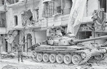  ?? SANA via Associated Press ?? Syrian army soldiers flash the victory sign near their tank in the Sukkari neighborho­od in eastern Aleppo. The Syrian government last week took control of eastern Aleppo for the first time since July 2012.