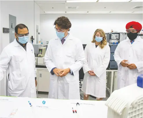  ?? Christine Muschi / REUTERS/ files ?? Prime Minister Justin Trudeau, accompanie­d by cabinet ministers Mélanie Joly and Navdeep Bains, right, speaks with Krishnaraj Tiwari about vaccines in August at the National Research Council of Canada in Montreal.