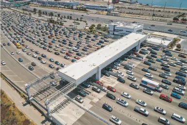  ?? Photos by Carlos Avila Gonzalez / The Chronicle ?? Traffic backs up at the Bay Bridge tollbooth on a recent Sunday. Weekend traffic on the bridge has been steadily increasing as Bay Area businesses reopen, but weekday totals remain below prepandemi­c levels.