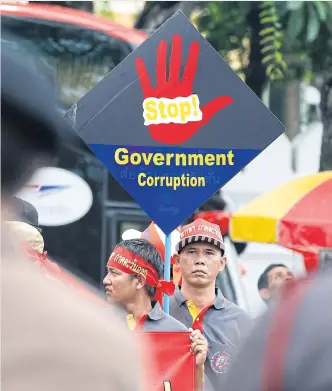  ??  ?? STOP THE GRAFT FIRST: A worker holds a banner reading ‘Stop Government Corruption’ during a march outside Government House, to mark Internatio­nal Workers’ Day on May 1.