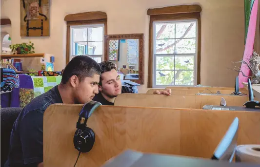  ?? EDDIE MOORE/JOURNAL ?? Horacio Lizama, left, from Medanales, and Juan Andres Maestas, from Abiquiú, work on one of several computers provided for people at the El Rito Library on Thursday. The area is receives funding for a broadband project.