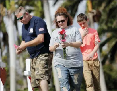  ?? ASSOCIATED PRESS ?? Bryan and Amber Gruzenksy place flowers on crosses with their son Joshua, 14, outside the Marjory Stoneman Douglas High School in Parkland, Fla., Sunday, where 17 people were killed in a mass shooting on Wednesday.