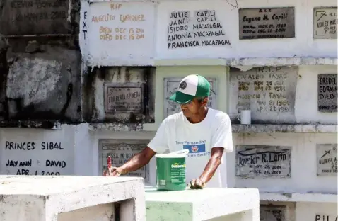  ?? -Chris Navarro ?? PAINT JOB.A worker paints a tomb at the Old Roman Catholic Cementery in the City of San Fernando in time for All Saints Day.