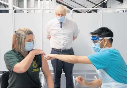  ?? Photo / AP ?? Britain's Prime Minister Boris Johnson watches first responder Caroline Cook receive an injection of a Covid-19 vaccine at Ashton Gate Stadium in Bristol, England.