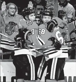  ?? CHRIS SWEDA/CHICAGO TRIBUNE ?? Blackhawks players John Quennevill­e (47) and Slater Koekkoek (68) surround teammate Jonathan Toews after Toews scored a goal against the Ducks on Saturday.