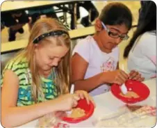  ??  ?? Haley Derr, left, and Simar Kaun crush graham crackers that represente­d the soil on which the landfill liner was placed.