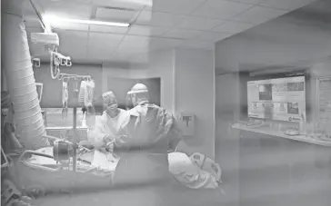  ?? JOE RONDONE/THE COMMERCIAL APPEAL ?? Registered Nurse Adam Olson, left, and and Ralph Micheletti, certified wound care nurse work with a patient inside Methodist University Hospital's COVID unit on Friday, Aug. 21, 2020. Editors Note: The patient's name, which was visible on the screen inside the hospital room, has been removed at the hospital's request in the interest of patient privacy.