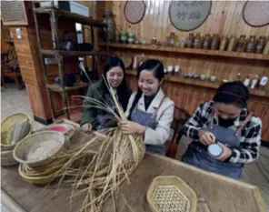  ?? ?? Yang Changqin (center) exchanges skills with colleagues at her bamboo weaving training base in Chishui