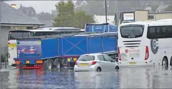  ??  ?? Floodwater rises up parked wheels in the Lochavulli­n Road car park.