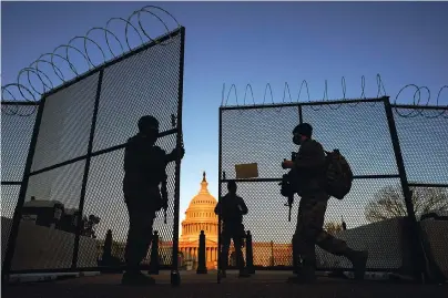  ?? The Associated Press ?? National Guard open a gate in the razor wire topped perimeter fence around the Capitol to allow another member in at sunrise on Thursday in Washington.