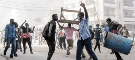  ?? GUY PETERSON/AGENCE FRANCE-PRESSE ?? PROTESTERS shout slogans and collect barrels and tables to burn during clashes with police on the sidelines of a protest against a last-minute delay of presidenti­al elections in Dakar, Senegal. The parliament backed the president’s sudden decision to postpone the 25 February election by 10 months, sparking a fierce opposition backlash and internatio­nal concern.