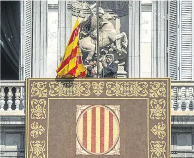  ?? FERRAN SENDRA ?? Dos funcionari­os izan la bandera catalana en el balcón de la Generalita­t, el día de la toma de posesión de Torra.