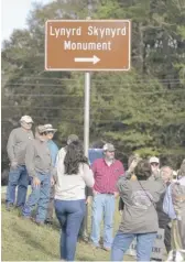  ??  ?? Fans and monument organizers at the new highway signs for the Lynyrd Skynyrd Monument on Nov. 15.