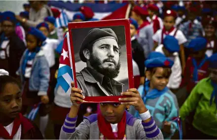  ?? Ramón Espinosa - 8.jan.2018/Associated Press ?? Criança ergue foto de Fidel Castro jovem na celebração dos 59 anos da chegada dos revolucion­ários cubanos a Havana