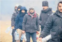  ?? LEONID SHCHEGLOV/BELTA ?? Migrants line up to collect drinking water as they gather Friday at the Belarus-Poland border near Grodno, Belarus.