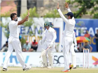  ?? AFP ?? Sri lanka’s Dilruwan perera (left) celebrates with his teammates after he dismissed South africa’s Quinton de Kock (centre). —