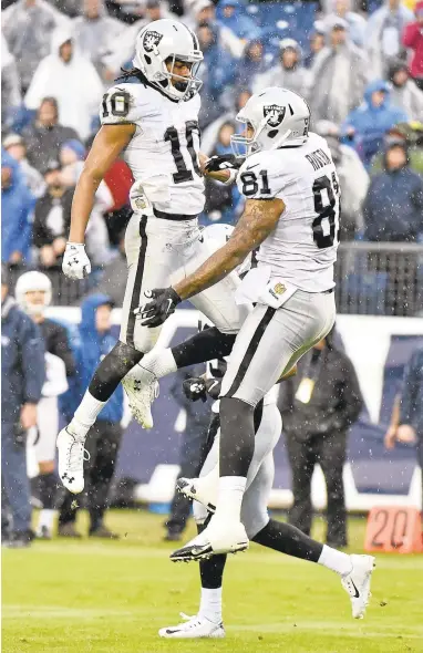  ?? FREDERICK BREEDON/GETTY IMAGES ?? Seth Roberts (10) is congratula­ted by Mychal Rivera after scoring the game-winning touchdown against the Titans on Sunday.