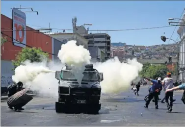  ??  ?? Un coche de la Policía chilena echa gas hacia manifestan­tes que protestan contra el gobierno en Valparaiso.